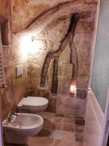 a bathroom with a white toilet and a sink at Cave Rooms Sassi in Matera