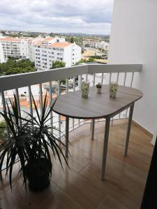 einen Holztisch auf einem Balkon mit zwei Pflanzen in der Unterkunft Lux Home in Albufeira
