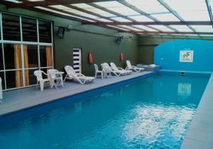 a swimming pool with white chairs and tables and a swimming pool at Hotel San Remo Majestic in Mar de Ajó