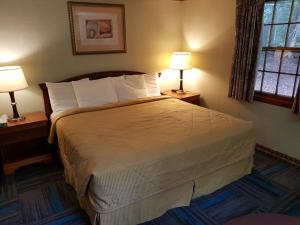 a bedroom with a bed with two lamps on two tables at Franconia Notch Motel in Lincoln