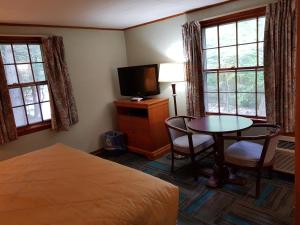 a bedroom with a bed and a table and a tv at Franconia Notch Motel in Lincoln