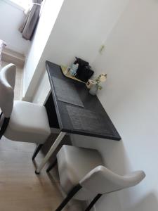 uma mesa de jantar com 2 cadeiras brancas e uma secretária em Pension Corper em Zandvoort