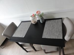 een zwarte tafel met twee stoelen en twee vazen bij Pension Corper in Zandvoort