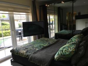 a bedroom with a tv and a couch and a bed at Beach bungalow Hellevoetsluis in Hellevoetsluis
