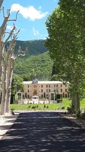 a building on a road with trees in front of it at Appartement 7 Château des Gipières in Montbrun-les-Bains