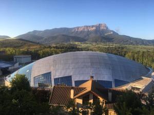 a large metal building with a mountain in the background at Apartamentos 7 Valles Jaca Centro in Jaca