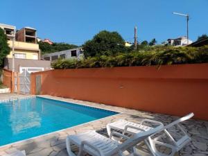 a swimming pool with two lawn chairs next to it at Pousada Sol do Araçá in São Sebastião