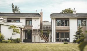 a white house with a porch and a staircase at Prieka Pietura in Sigulda