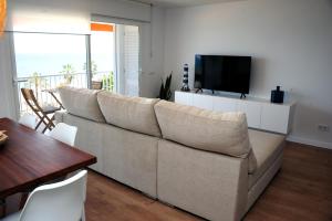 a living room with a large couch and a television at Apartamento frente al mar in Canet de Mar