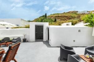 a white house with a black door and chairs at Casa d'Argento in Éxo Goniá