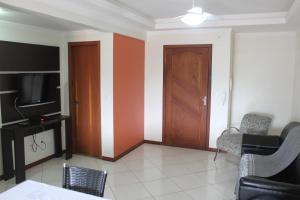 sala de estar con puerta de madera y TV en Apartamentos Morada do Sol, en Piratuba