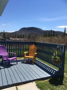 two chairs sitting on a deck with a fence at Down Home Accommodations in Rocky Harbour