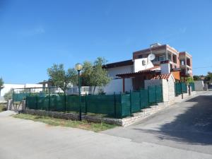 a house with a green fence next to a street at Apartman Duje in Petrcane