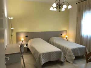 1 dormitorio con 2 camas y lámpara de araña en Borgo Barucchella, en SantʼAndrà