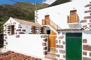 una casa blanca con una puerta verde en TenoHomes The Sunset Escape in Carrizales, Masca, en Buenavista del Norte