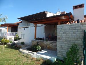 a house with a brick retaining wall and a wooden pergola at Apartman Duje in Petrcane