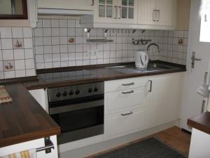 uma cozinha com armários brancos e um forno de fogão preto em Ferienhaus Milena em Lieser