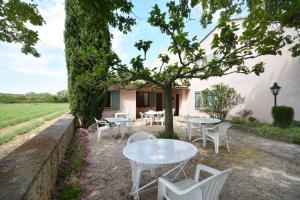 un patio con tavoli e sedie bianchi sotto un albero di Chambre d'Hôtes Au Vieux Chêne a Grillon