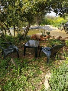 tres sillas negras y una mesa en el césped en Cabin In The View, en Hararit