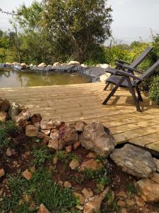 eine Holzterrasse mit einer Bank auf einem Teich in der Unterkunft Cabin In The View in Hararit