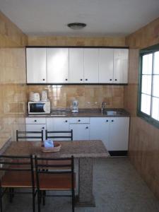 Una cocina con gabinetes blancos y una mesa y sillas. en Bungalows Boston, en Puerto Rico de Gran Canaria 9 fotos más