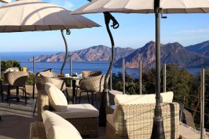 een patio met een tafel, stoelen en parasols bij Hotel Scandola in Piana