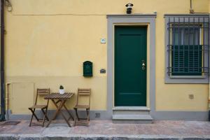 einen Tisch und Stühle vor einem Gebäude mit grüner Tür in der Unterkunft Casa Laurentius in Pisa