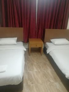 two beds in a room with a red curtain at Al-Houriat Hotel in Amman