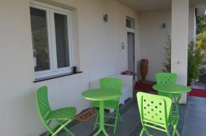 un patio con sillas y mesas verdes y una ventana en Quiero Más B&B, en San Nicola Arcella