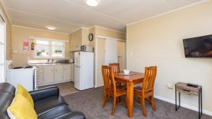 a kitchen and dining room with a table and chairs at Waitangi Beach Bach 30B in Paihia