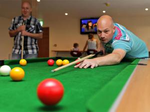 a man laying on a pool table with cue balls at Causeway Coast Wigwams in Bushmills