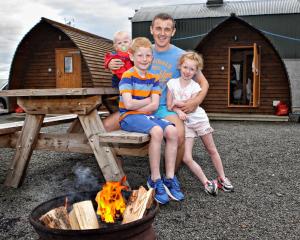 a man and two children sitting on a picnic table next to a fire at Causeway Coast Wigwams in Bushmills