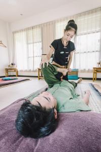 a woman sitting on the floor with a woman getting a massage at The River Resort in Champasak