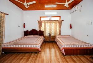 two beds in a room with wooden floors at Vamoose Madhumita Homestay in Guwahati