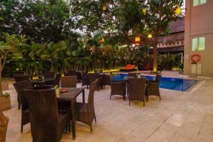 un restaurante con mesas y sillas y una piscina en Sunwood Hotel Arianz Mataram en Mataram