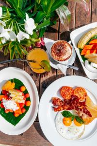 - une table en bois avec des assiettes de nourriture pour le petit-déjeuner dans l'établissement Tamanu Beach, à Arutanga