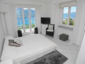 Habitación blanca con cama, escritorio y ventanas en Casa Albaredo App 2309, en Brione sopra Minusio