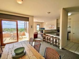 a kitchen and dining room with a wooden table with chairs at Lornebeach Apartments in Lorne