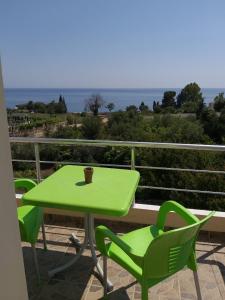 a green table and chairs on a balcony with the ocean at Hotel Afrodite in Dhërmi +36 photos