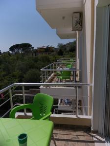 a row of green chairs and tables on a balcony at Hotel Afrodite in Dhërmi