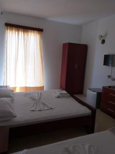 a bedroom with a bed with a dresser and a window at Hotel Afrodite in Dhërmi