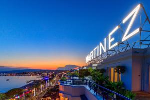 a building with a sign on top of it at night at Hôtel Martinez, in The Unbound Collection by Hyatt in Cannes