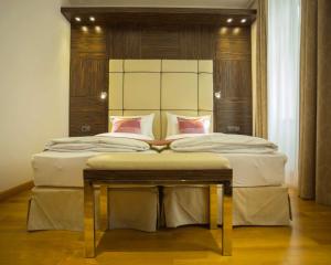 um quarto com uma cama grande com lençóis brancos e almofadas cor-de-rosa em Best Western Plus Hotel Arcadia em Viena