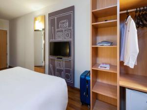 a hotel room with a bed and a tv and shelves at ibis Sao Jose in São José