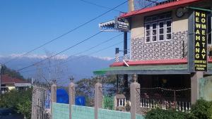 a building with a fence and mountains in the background at Vamoose Newahang in Pedong