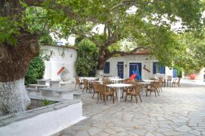a patio with tables and chairs under a tree at Sariza Spring Hotel in Andros