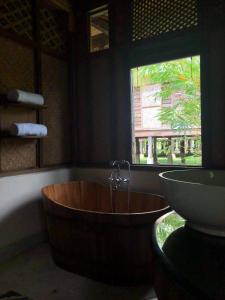 
a bath tub sitting in a bathroom next to a window at Kunang Kunang Heritage Villas in Pantai Cenang
