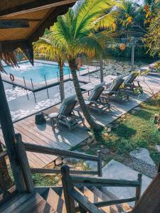 een groep stoelen en een palmboom naast een zwembad bij Kunang Kunang Heritage Villas in Pantai Cenang