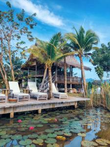 a resort with palm trees and chairs and a pond at Kunang Kunang Heritage Villas in Pantai Cenang