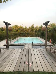 a swimming pool with a wooden deck and a boardwalk at Kunang Kunang Heritage Villas in Pantai Cenang